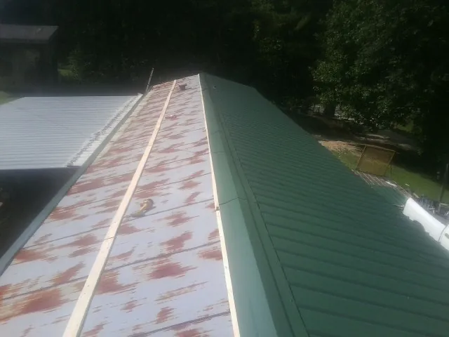 Old rusted panels beside newly installed green metal roofing — Wind Damage Roof Repair by Roofing Brothers in West Alexandria