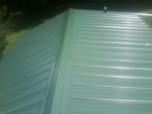 New green metal panels meeting at the ridge of a roof — Flat Roof Repair work by our crew in West Alexandria
