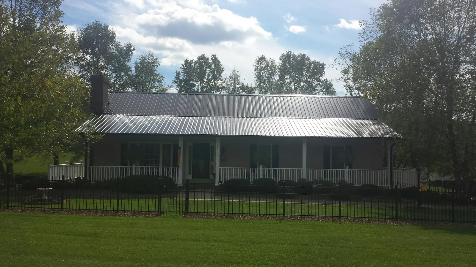 Gray metal roof on a brick ranch with a full width front porch — Gutter Guard Installation work by our crew in West Alexandria