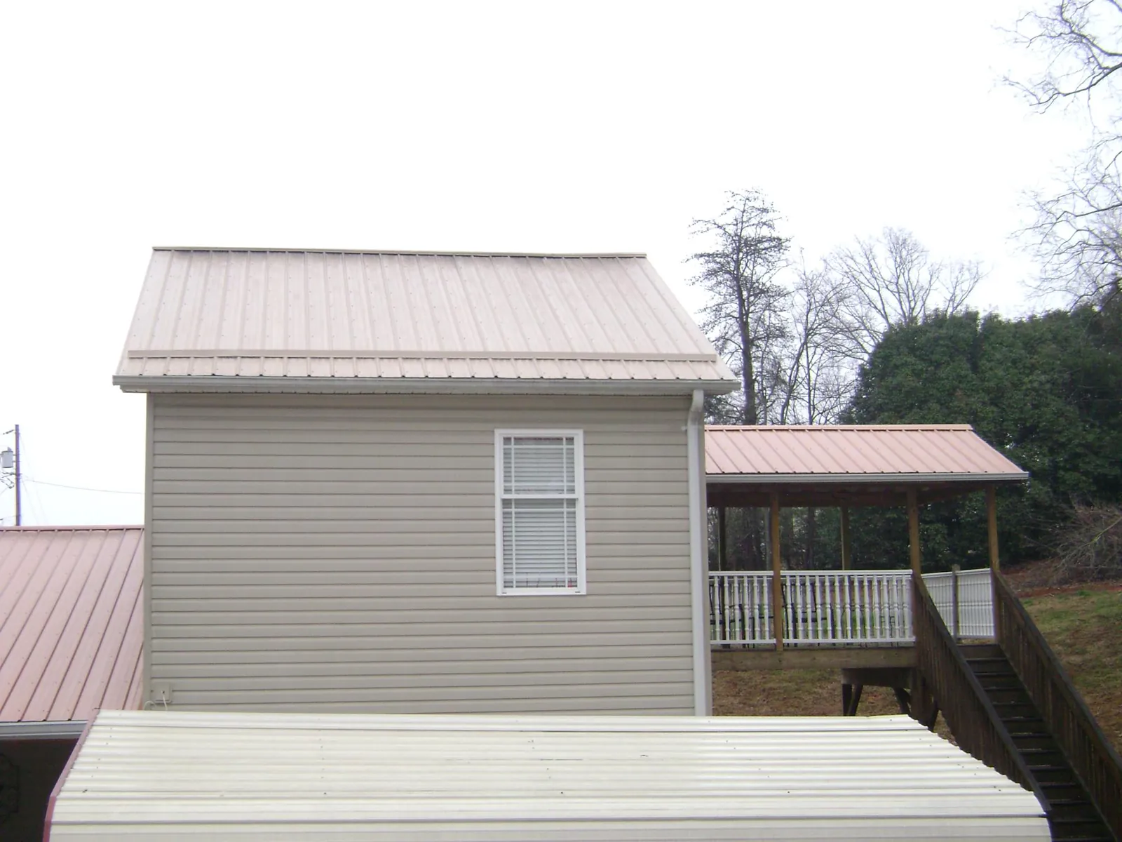 Tan metal roofs on a two story addition and attached porch, from a Roof Replacement job in West Alexandria