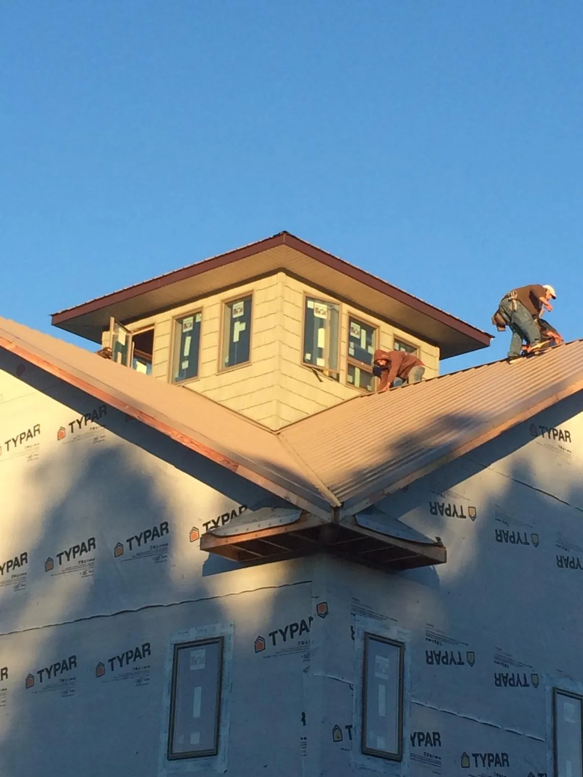Roofers working around a rooftop cupola on a new metal roof at sunset — Roof Waterproofing in West Alexandria by Roofing Brothers